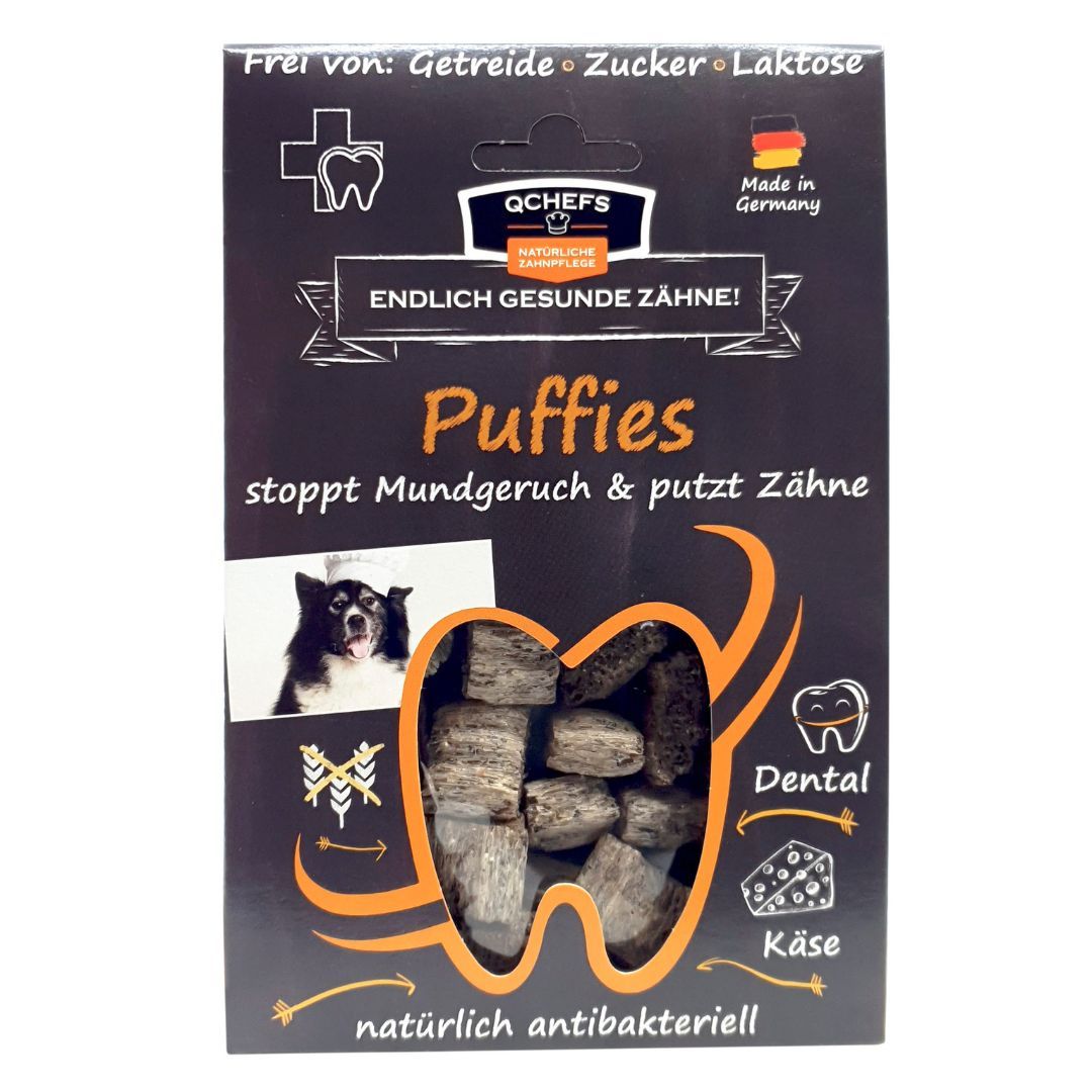 Verpackung mit QCHEFS Puffies. Schwarzer Karton mit Produktnamen, Hundefoto und Zahn-Illustration. Text: Endlich gesunde Zähne!