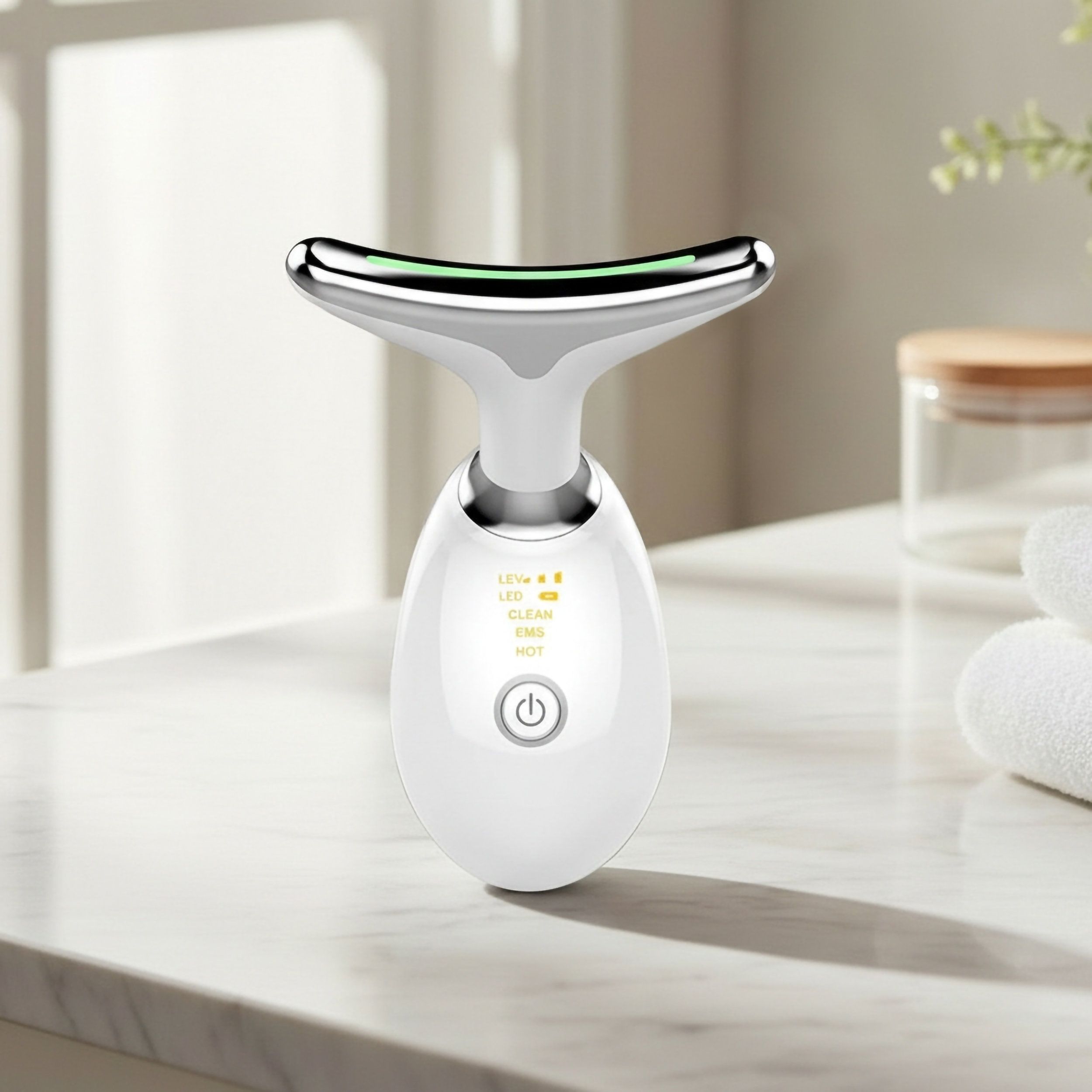 Weißes, ergonomisches Gerät zur Gesichtspflege. Silberfarbener Kopf. LED-Anzeige und Bedienknopf.