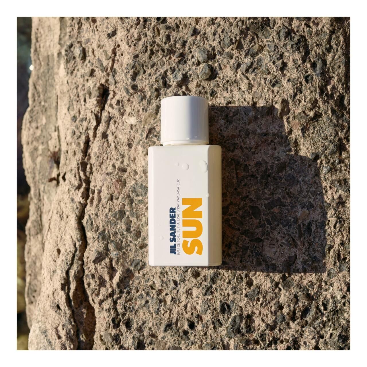 Weißer Flakon mit weißem Deckel. Aufschrift SUN in Orange. JIL SANDER-Logo und Text.
