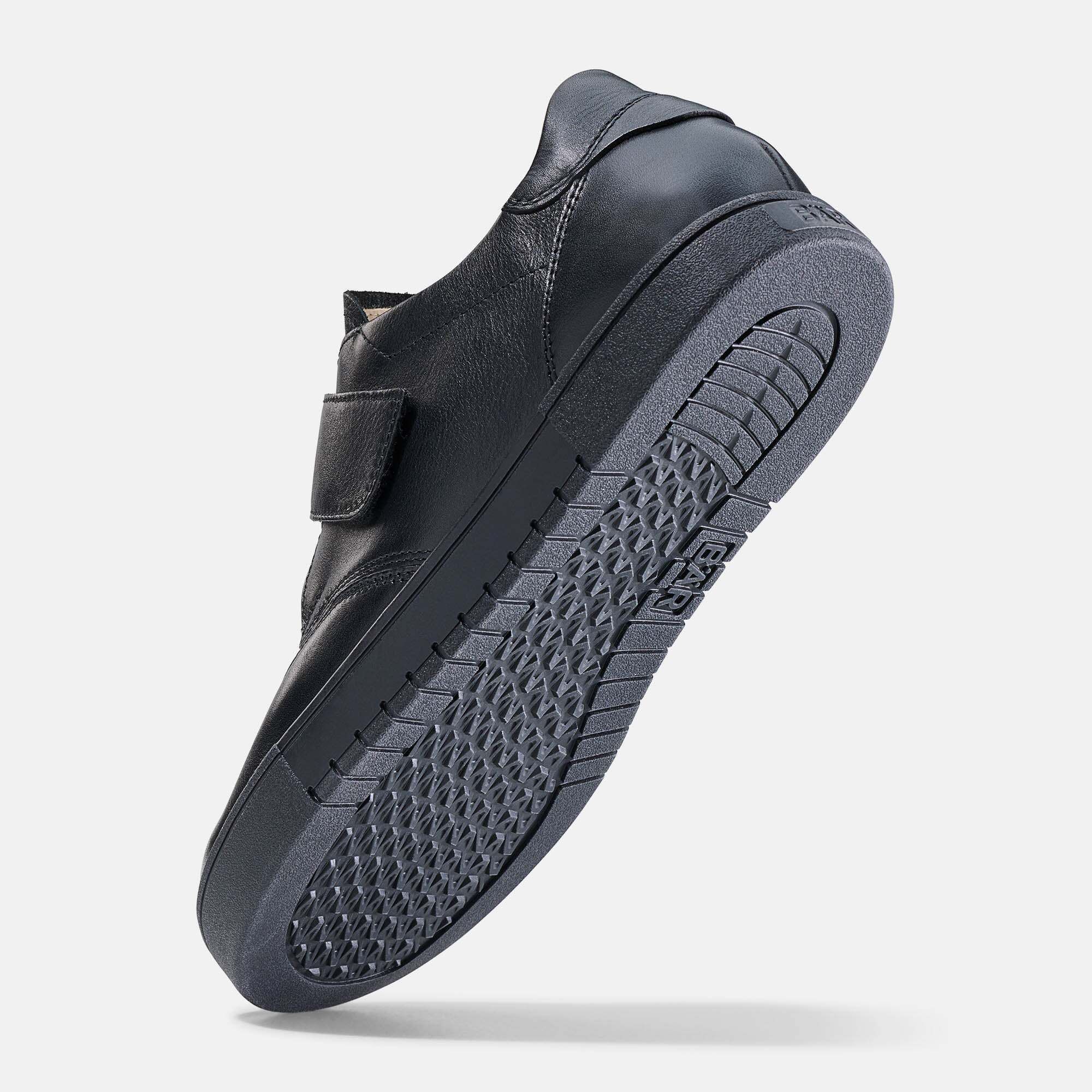 Schwarzer Sneaker aus Leder mit Klettverschluss und profilierter Sohle.