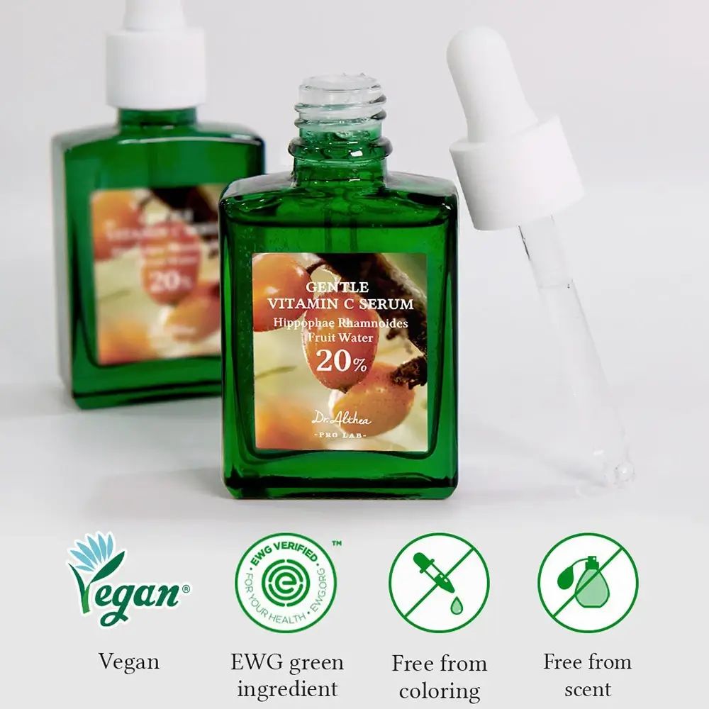 Zwei grüne Flaschen mit Pipetten. Vegan-Logo, EWG-Zertifizierung, Symbole für frei von Farbstoffen und Duftstoffen.