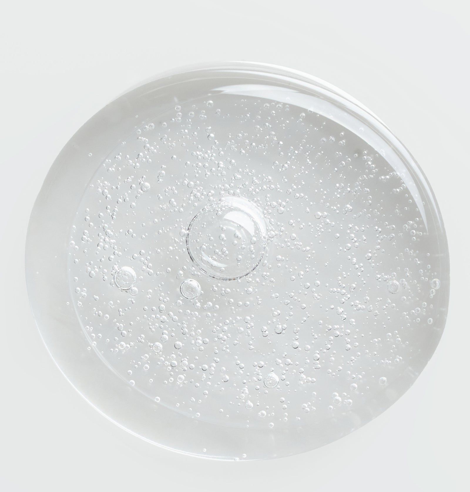 Nahaufnahme von Serum mit Bläschen. Klare, transparente Flüssigkeit. Runde Form, helle Beleuchtung.