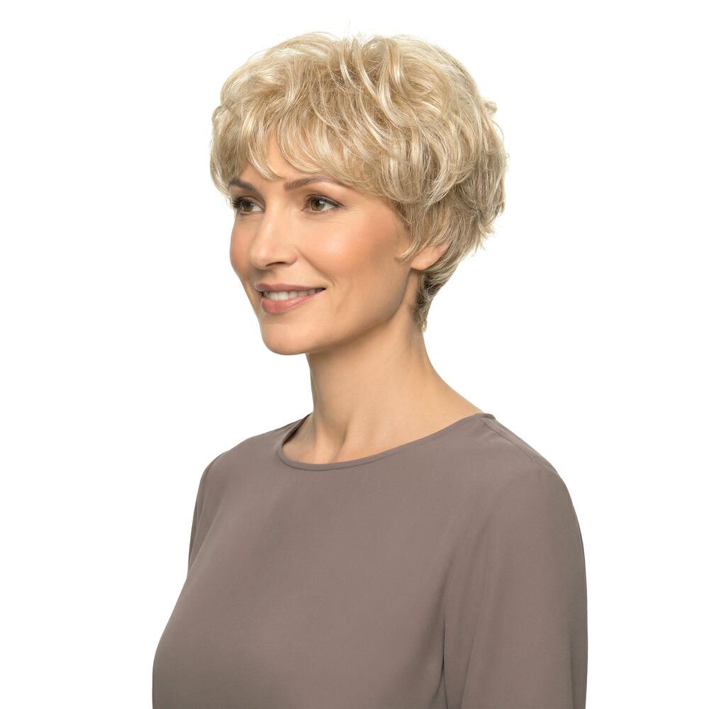 Blond gelockte Perücke. Seitenansicht einer lächelnden Frau mit braunem Oberteil.