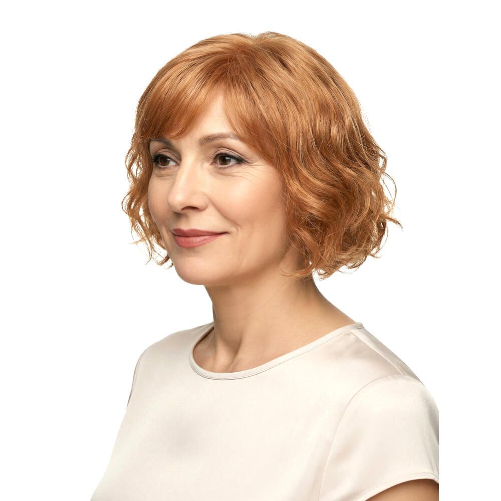 Frau mit rotblonder Perücke. Welliges Haar, Pony. Seitenansicht, helles Oberteil.