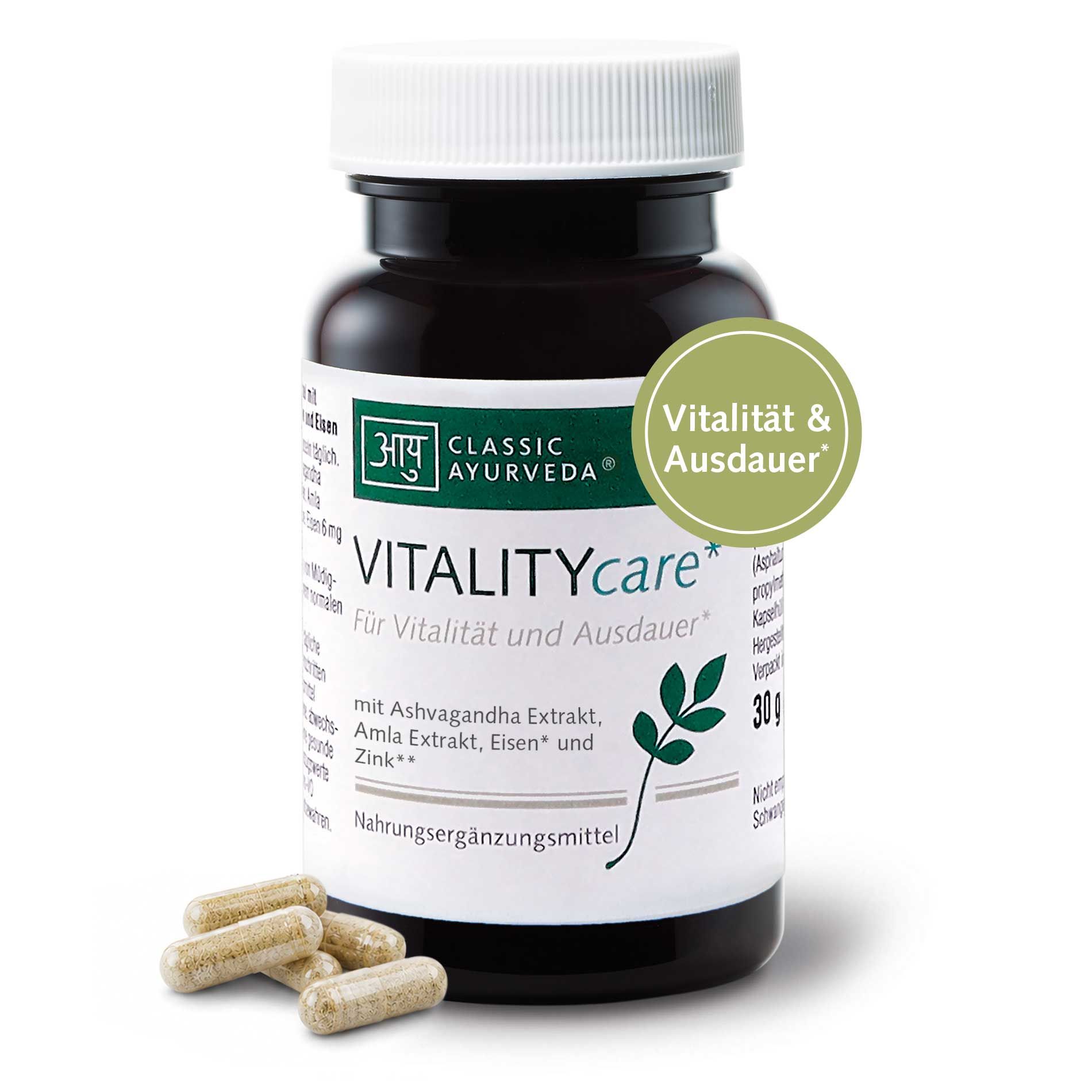 Dunkle Glasflasche mit weißem Deckel, Etikett 'VITALITYcare', 'CLASSIC AYURVEDA', 30g. Kapseln liegen daneben.