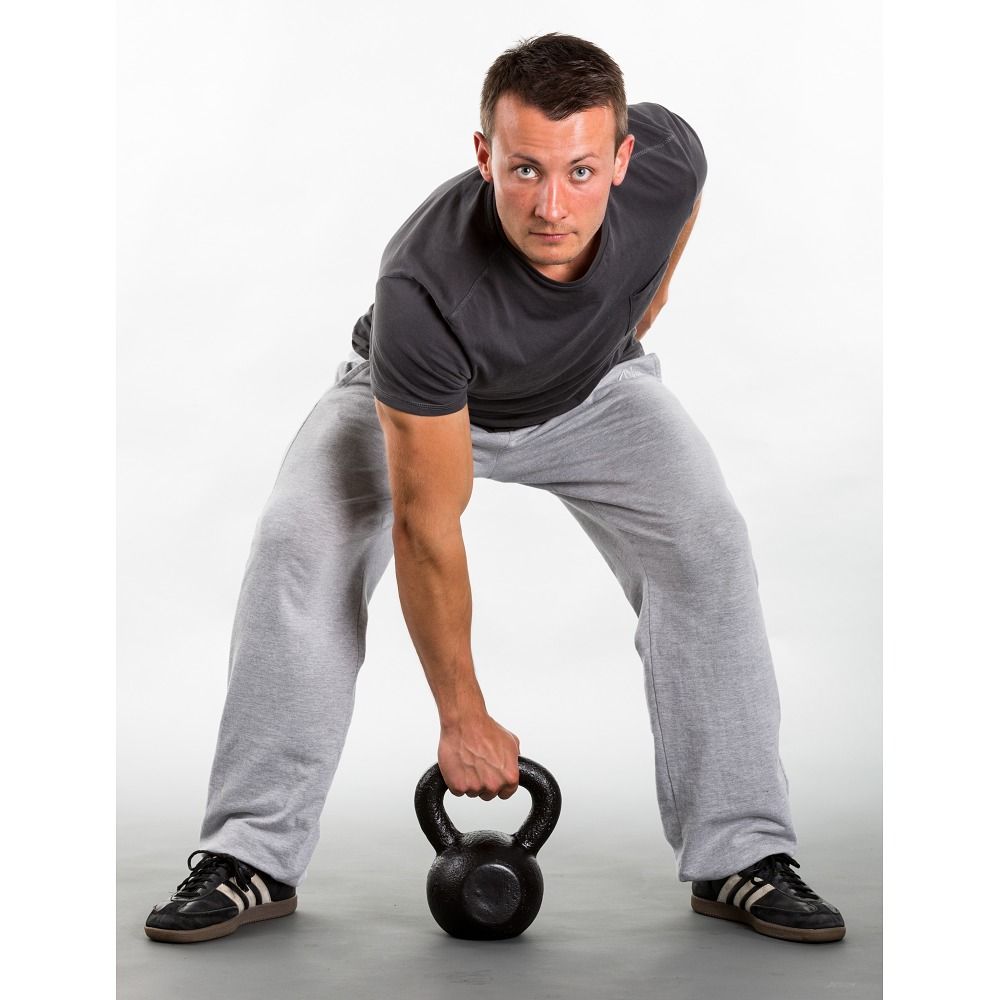 Mann mit Kettlebell. Graues T-Shirt und Hose. Schwarze Schuhe. Weißer Hintergrund.