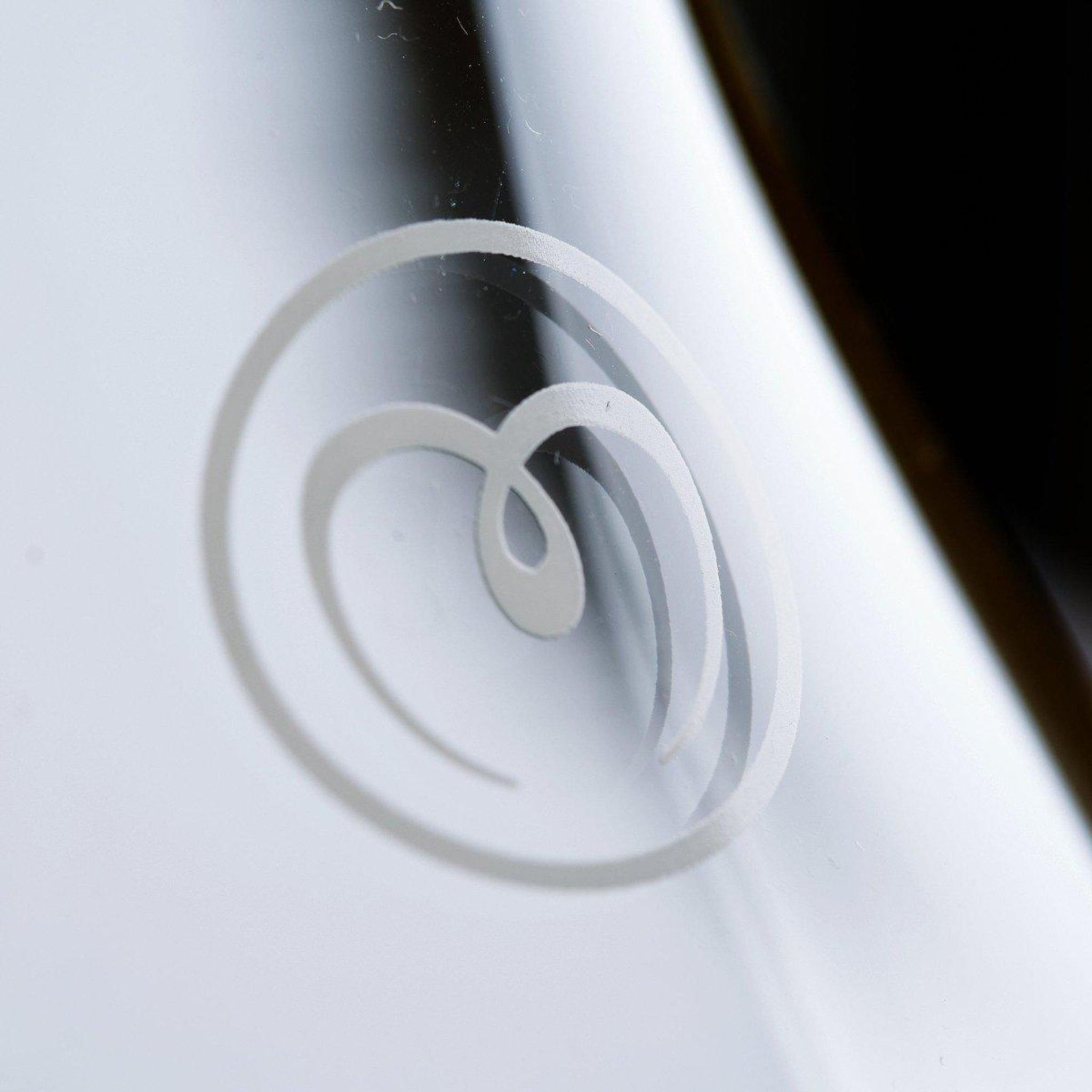 Nahaufnahme des MAYU-Logos auf einer Wasserkaraffe. Weißes, geschwungenes Design auf Glas.