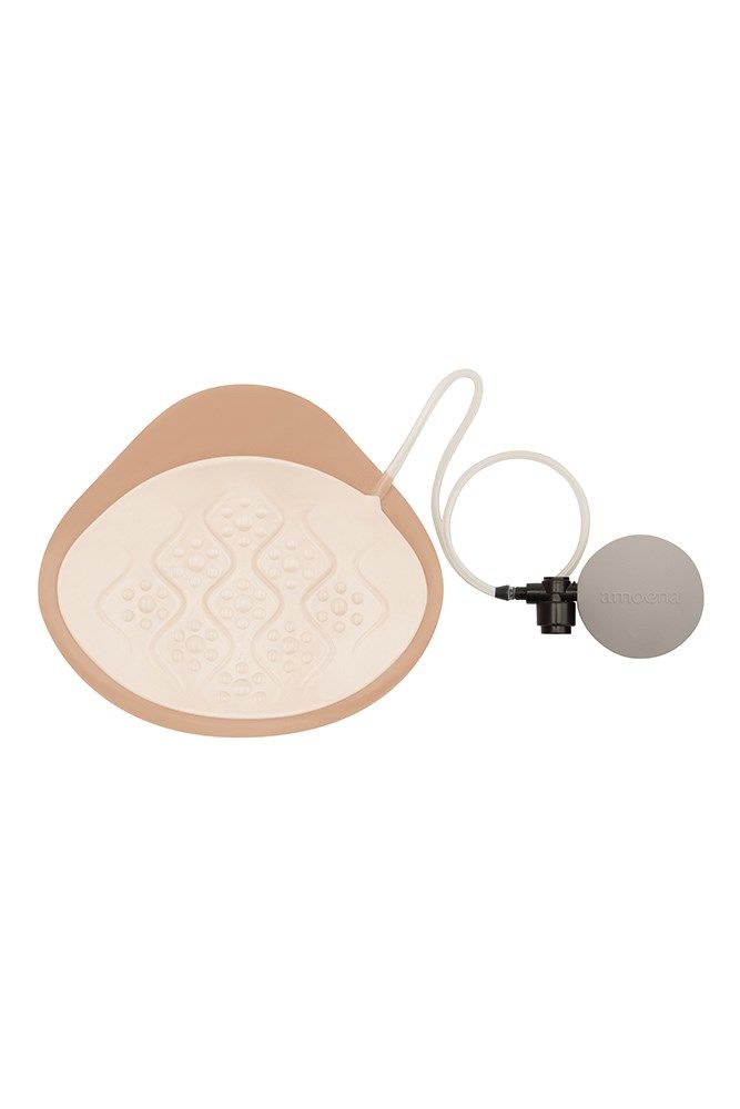 Brustepithese mit Zubehör. Beige, tropfenförmig. Innenseite mit Muster. Mit Pumpe und Schlauch. Für medizinische Zwecke.
