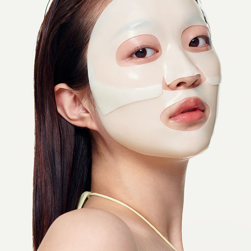 Gesichtsmaske auf Gesicht. Weiße Maske bedeckt Augen, Nase und Mund. Person mit langen, dunklen Haaren und gelbem Oberteil.