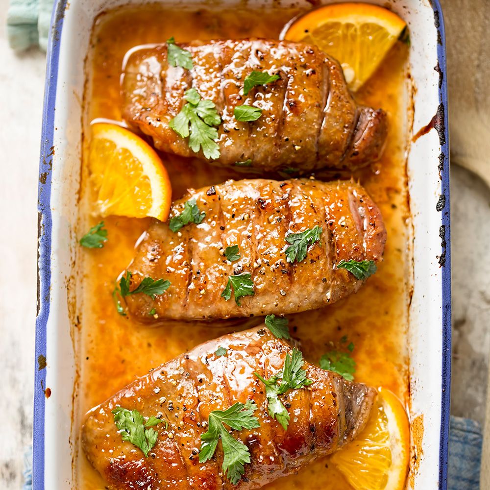 Gebratene Entenbrust in Auflaufform. Mit Orangenscheiben und Petersilie garniert. Draufsicht.