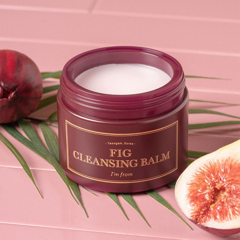 Offener Tiegel mit weißem Inhalt, umgeben von Feige und Blatt. Goldfarbene Schrift: FIG CLEANSING BALM, I'm from.