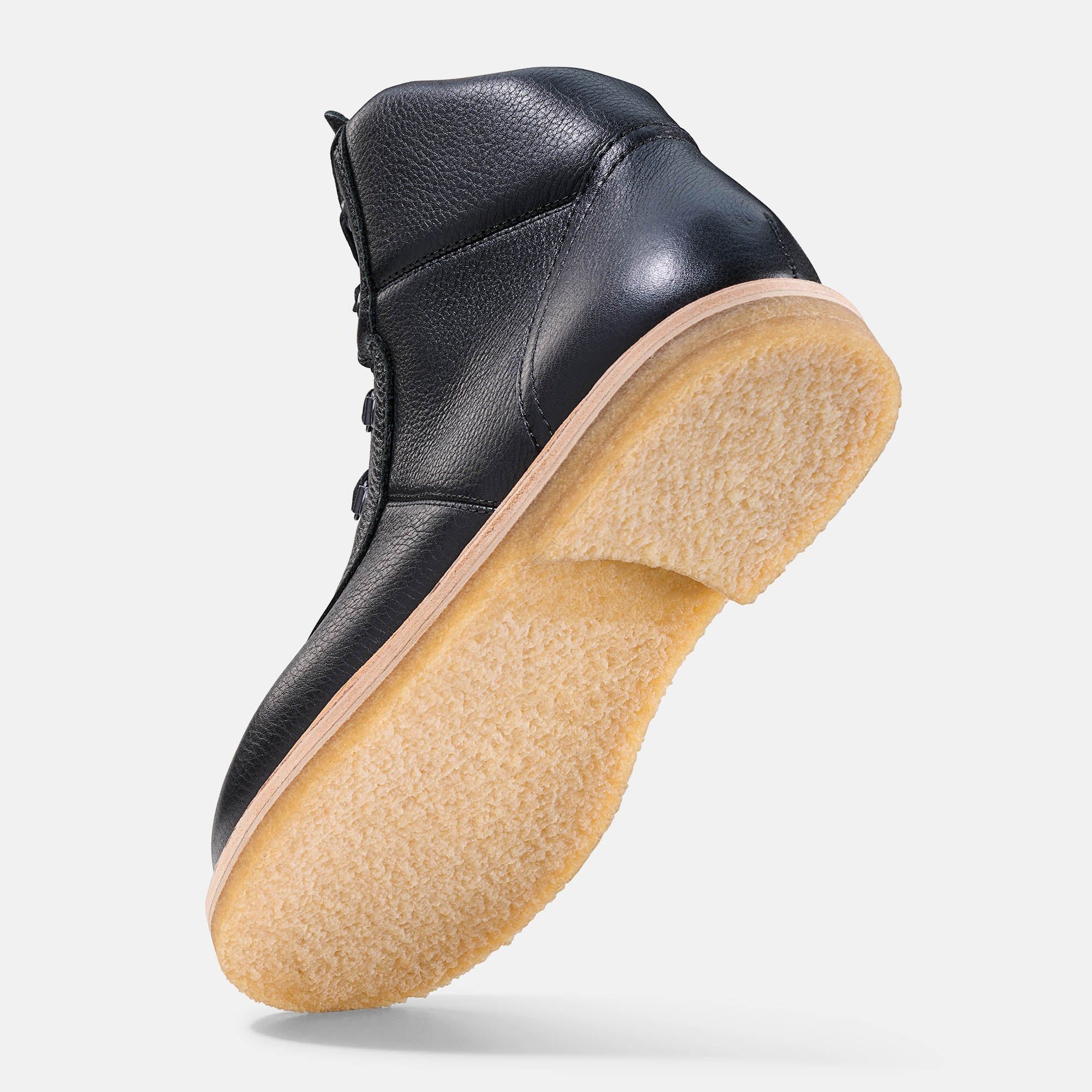 Schwarze Stiefelette mit heller Sohle. Lederoptik. Sohle und Unterseite sichtbar.