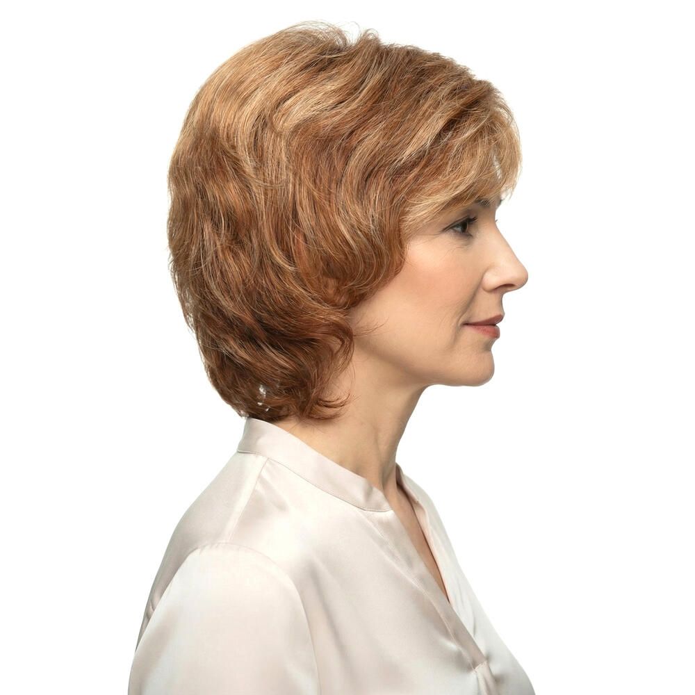 Frau mit Perücke, blond-braune Haare, Seitenansicht. Hellbraune Strähnen, schulterlange Frisur. Trägt eine helle Bluse.