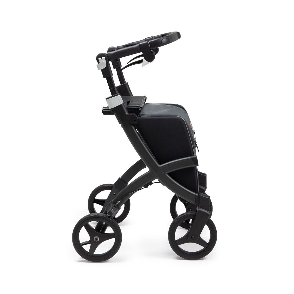 Schwarzer Rollator, Seitenansicht. Vier Räder, Handgriffe, Tasche.