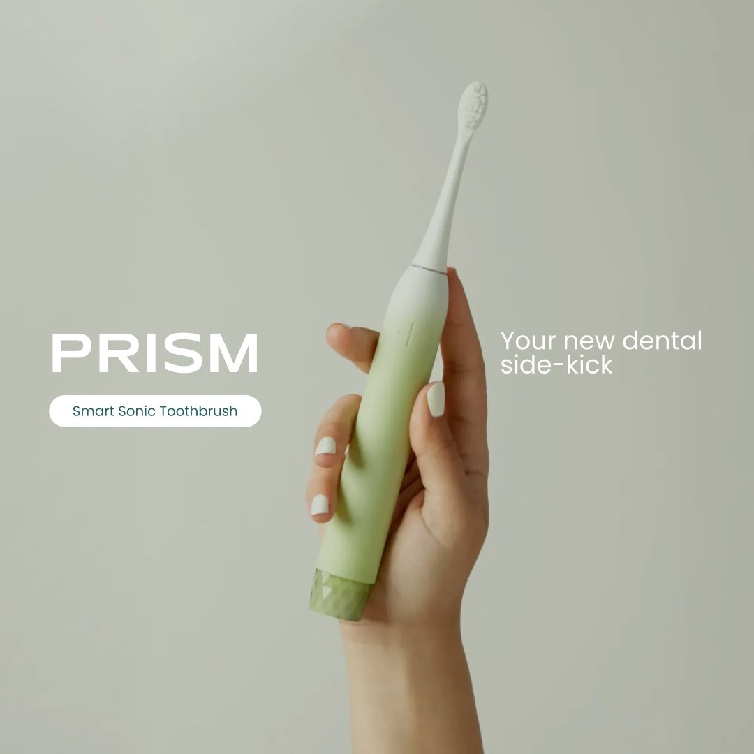 Hand hält eine grüne Be Lucent Prism Sonic Elektrische Zahnbürste.