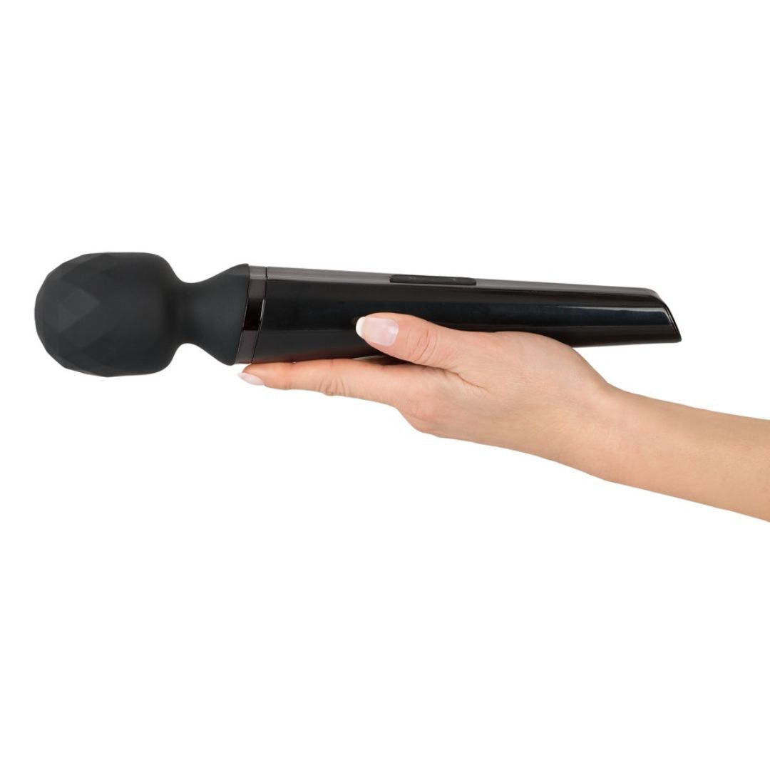 Schwarzer Massage-Vibrator, gehalten in einer Hand. Kegelförmiger Griff, geriffelte Spitze.