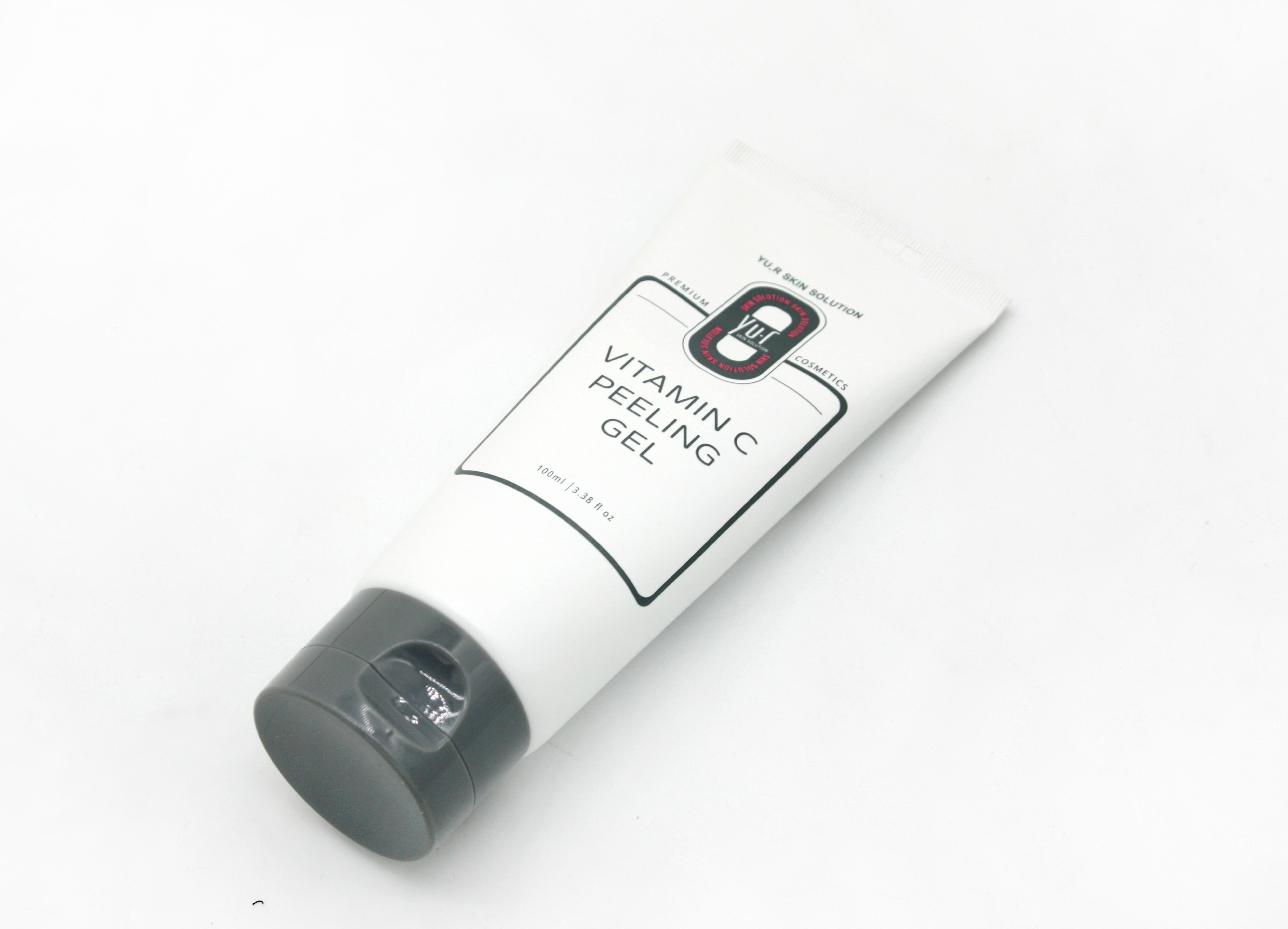 Weiße Tube mit grauer Kappe und Aufschrift Vitamin C Peeling Gel. Schräg von oben fotografiert.