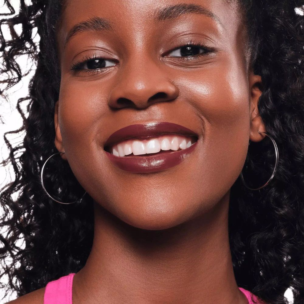 Nahaufnahme eines lächelnden Gesichts mit Lippenstift. Die Lippen sind mit einem dunklen Lippenstift geschminkt.