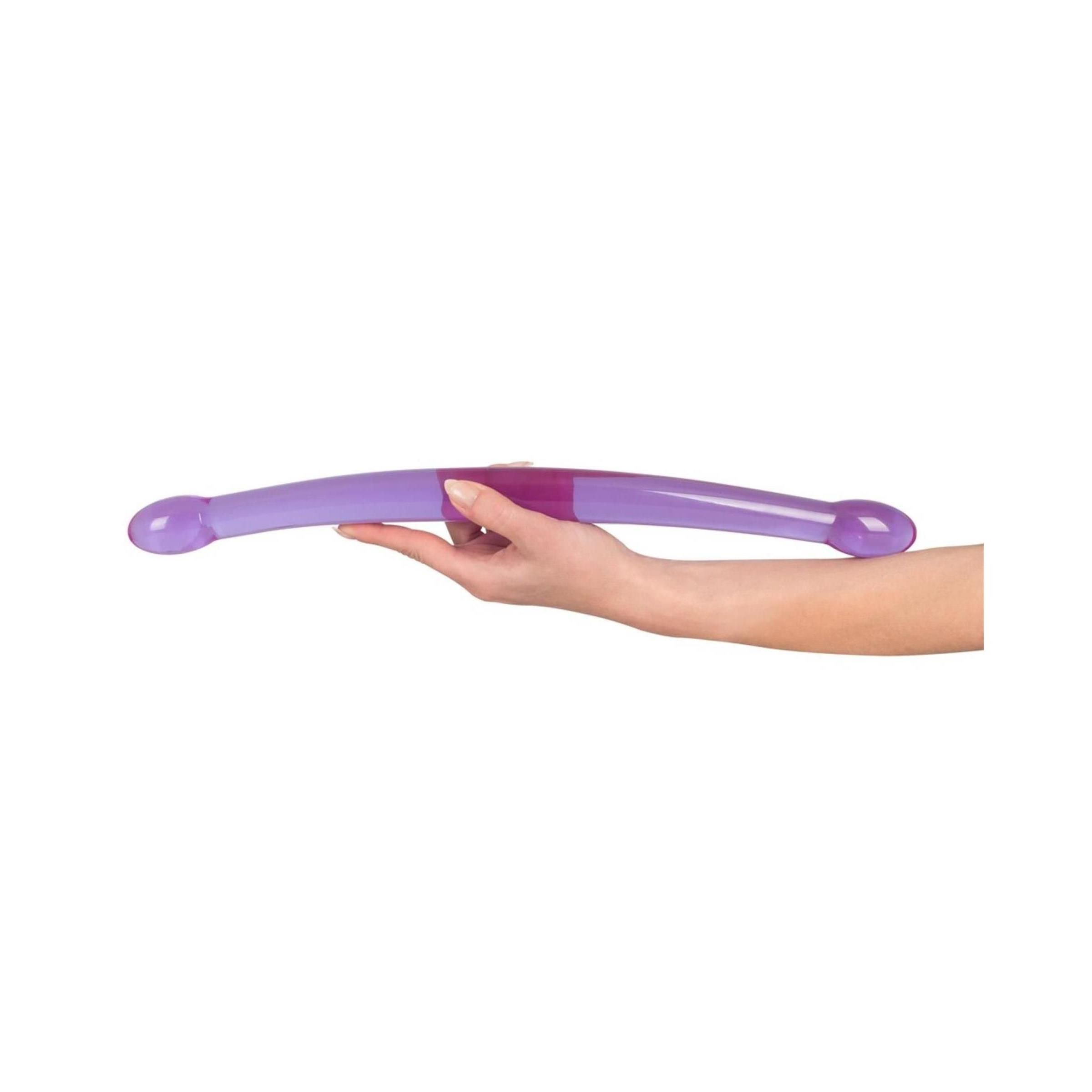 Lila Wellness-Produkt mit zwei abgerundeten Enden. Gehalten in einer Hand.