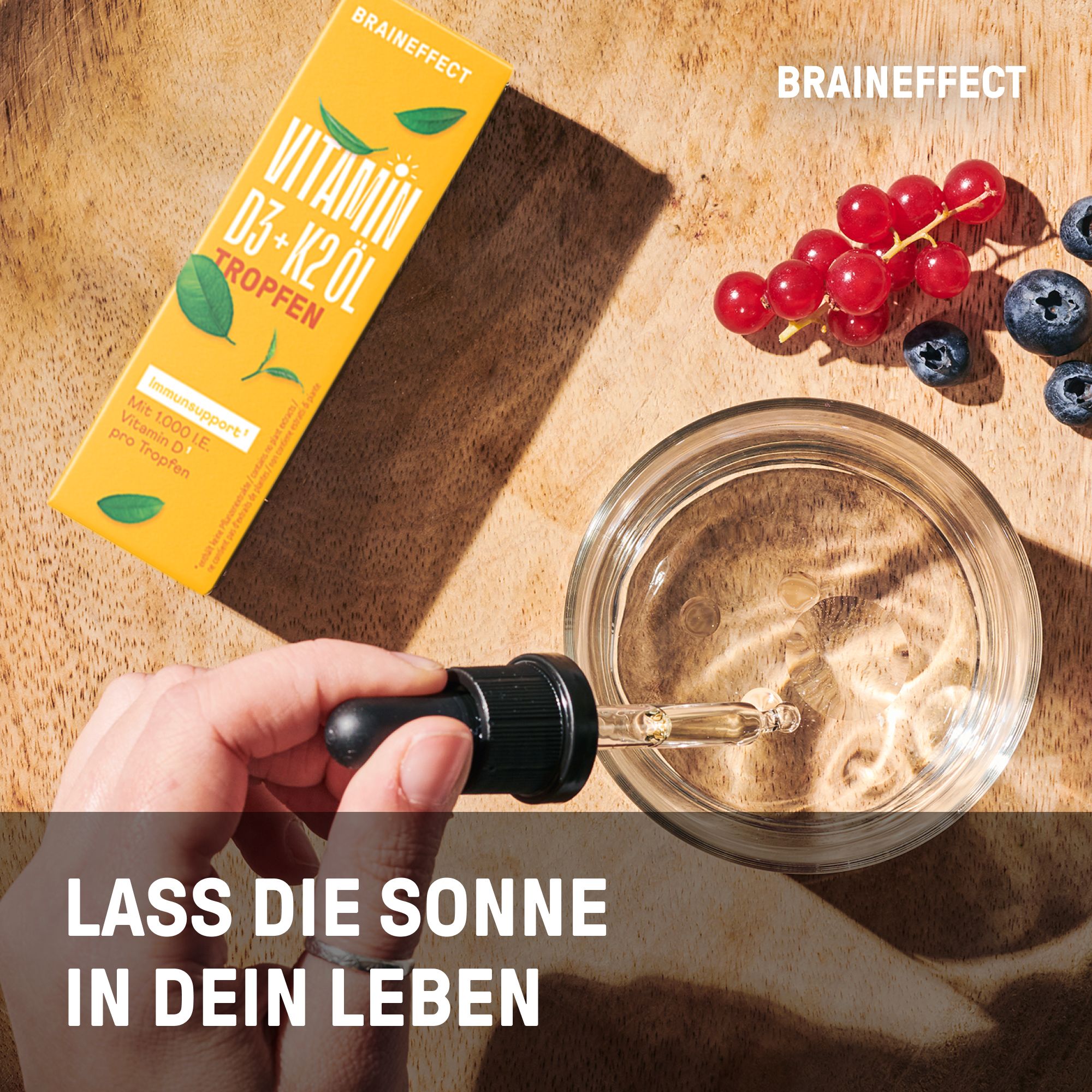 Hand mit Tropfer über Glas mit Flüssigkeit. Daneben Verpackung. Text: Lass die Sonne in dein Leben. Marke: BRAINEFFECT.