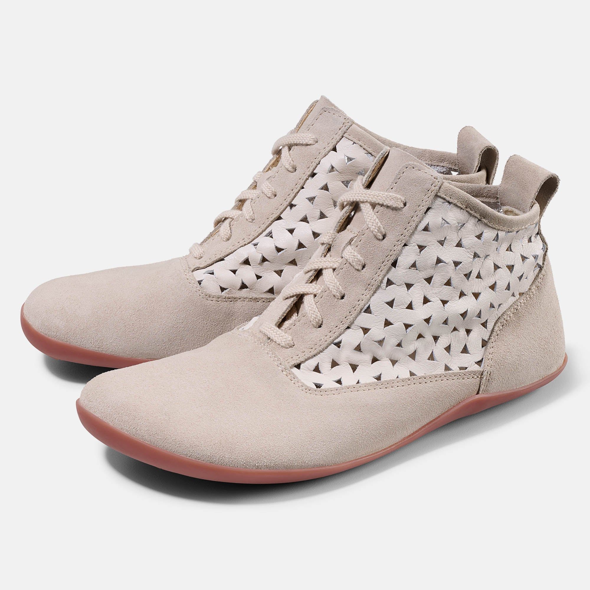 Beige Stiefeletten mit Schnürung und Dreiecksmuster. Rote Sohle. Seitliche Aussparungen. Obermaterial aus Wildleder.