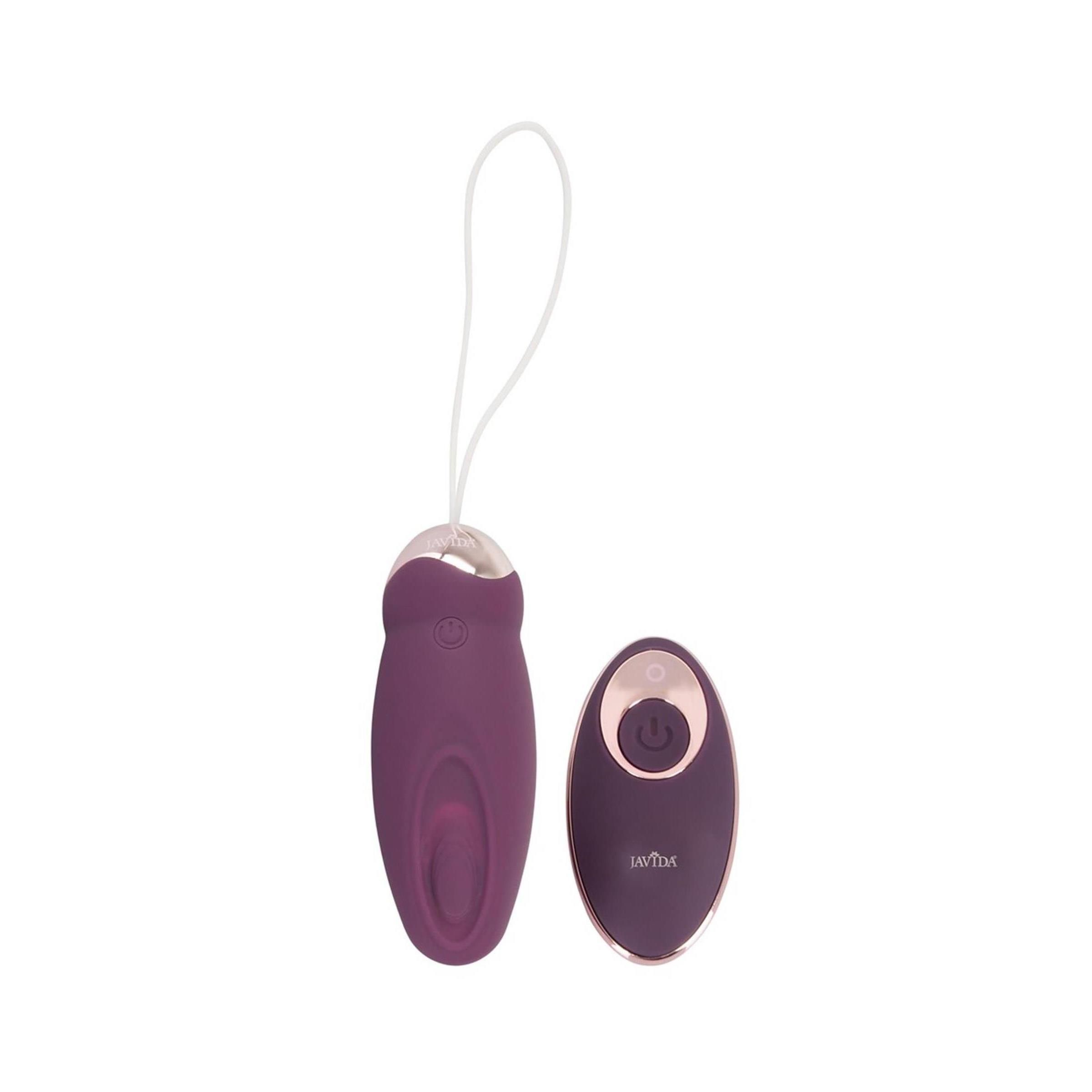 Lila Vibrationsgerät mit weißer Schlaufe und Fernbedienung. Goldfarbene Akzente. Auf weißem Hintergrund.