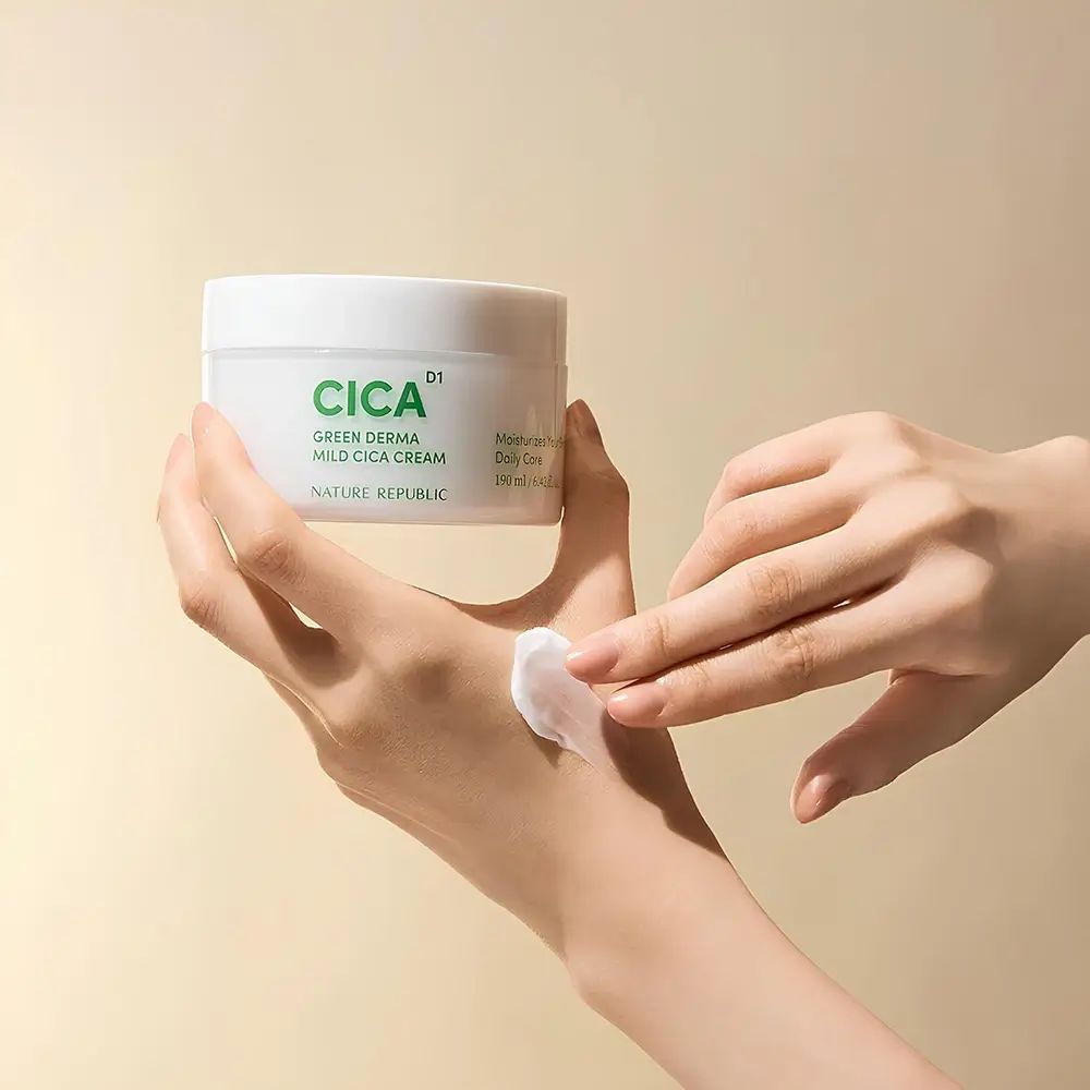 Hände tragen Creme auf. Weißer Tiegel mit grüner CICA-Aufschrift, Green Derma Mild Cica Cream. Creme auf der Hand.