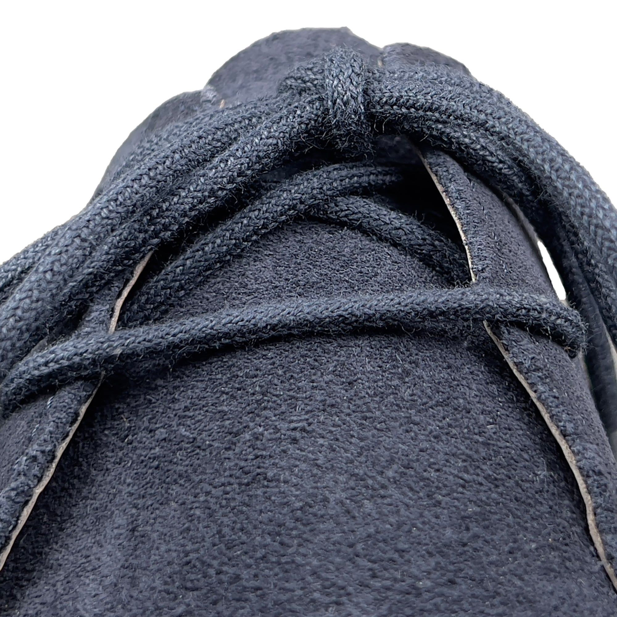 Nahaufnahme der Schnürsenkel eines blauen Wildlederschuhs. Hellgrauer Hintergrund.