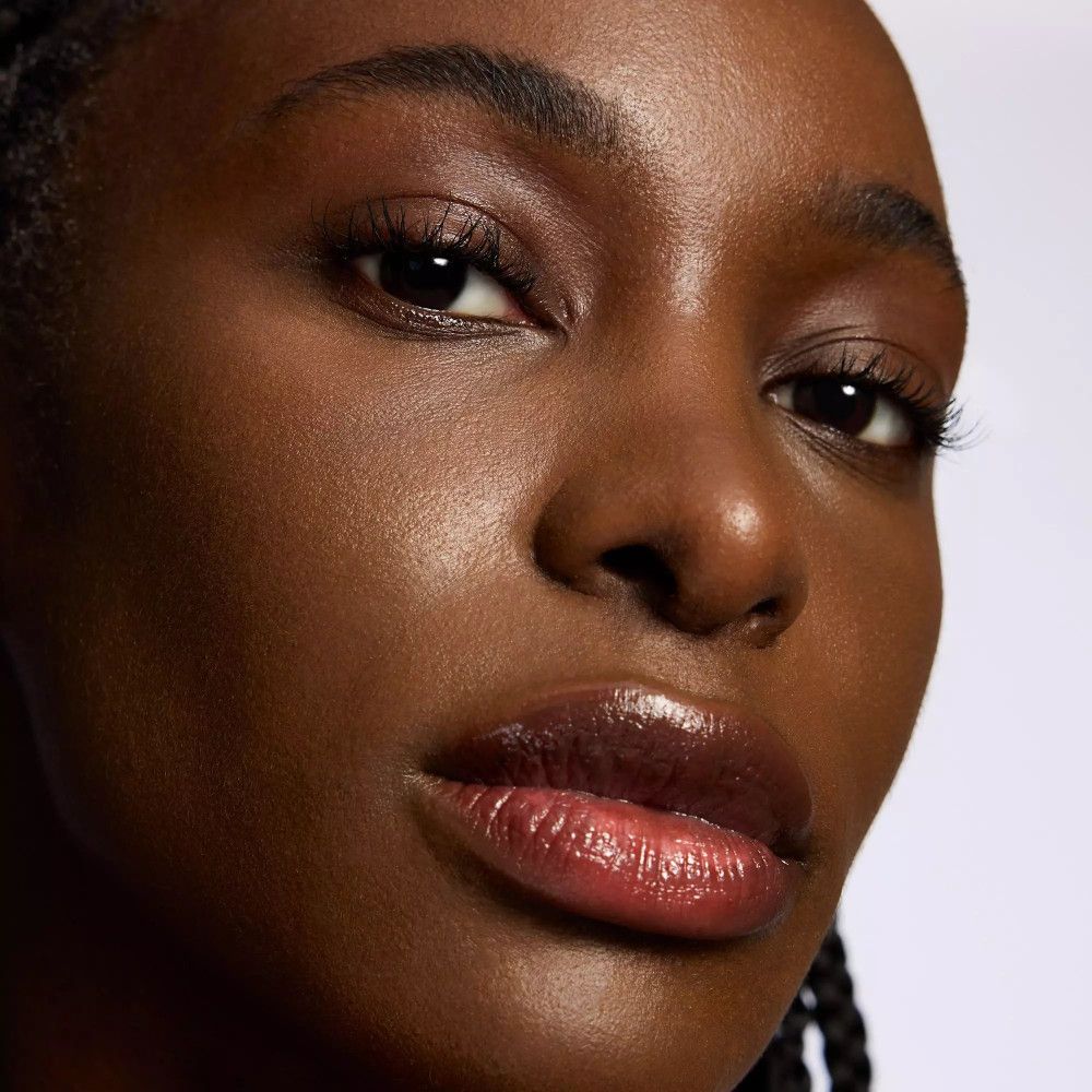 Nahaufnahme eines Gesichts. Dunkle Haut, dunkle Haare. Geschminkte Lippen und Augen.