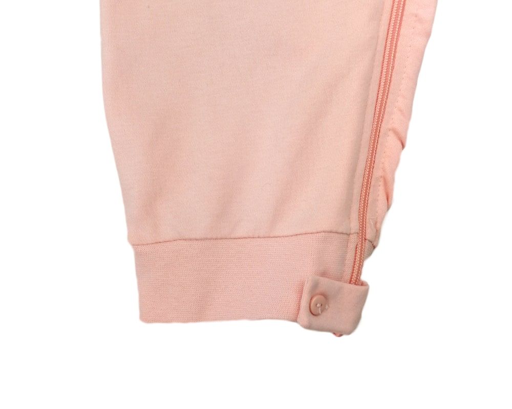Detailansicht des apricotfarbenen Pflegeoveralls. Manschette mit Knopf am Beinabschluss.