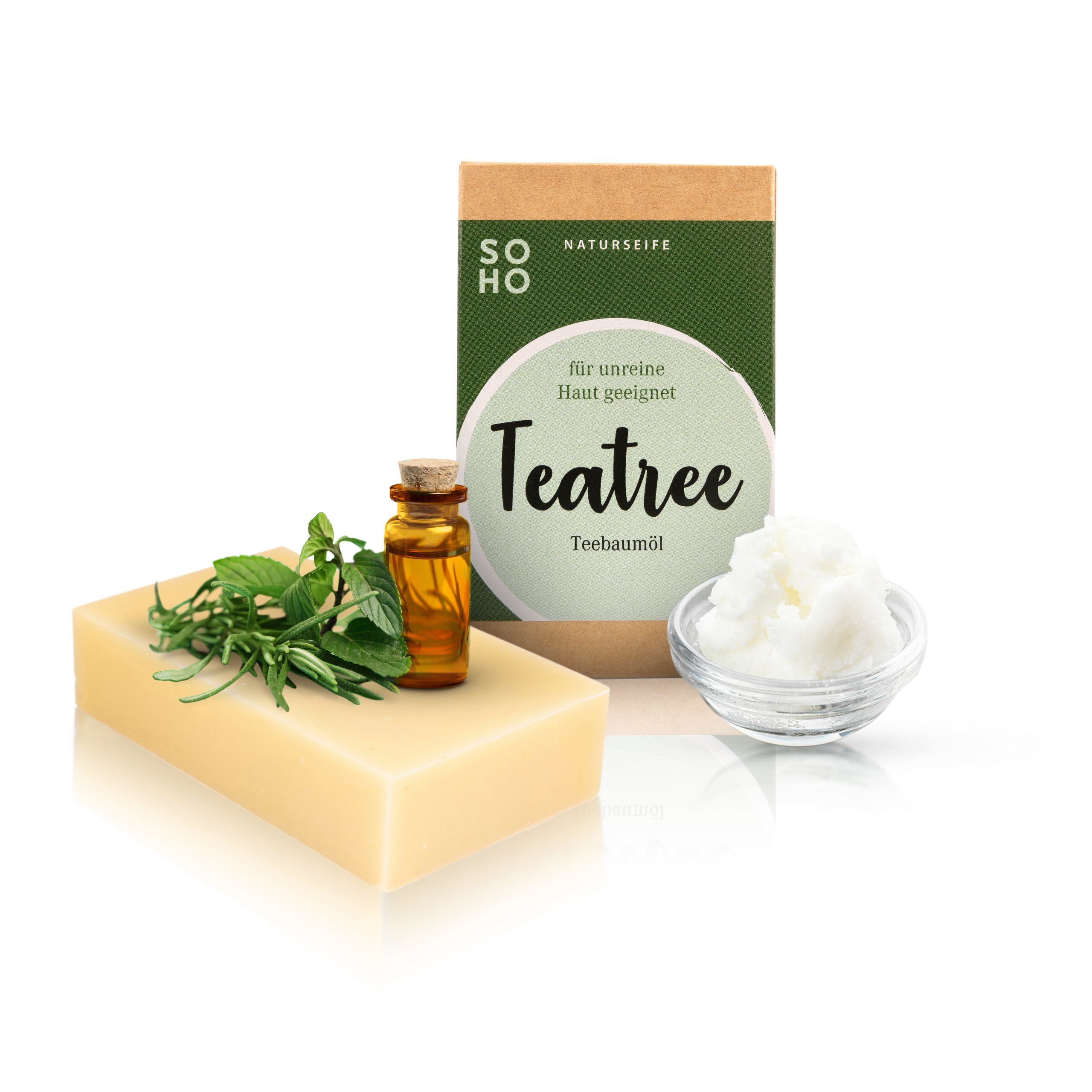 Rechteckige Seife, braune Verpackung mit grünem Etikett. Daneben eine kleine Flasche Öl, Kräuter und eine Schale mit weißer Creme.