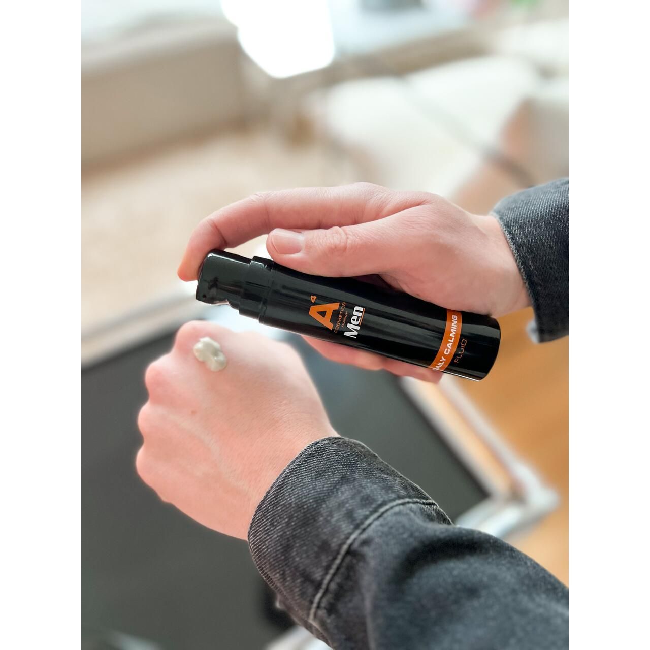 Person hält schwarze Flasche. Produkt wird auf Hand aufgetragen. Aufschrift: A4 Cosmetics Men, Daily Calming Fluid.