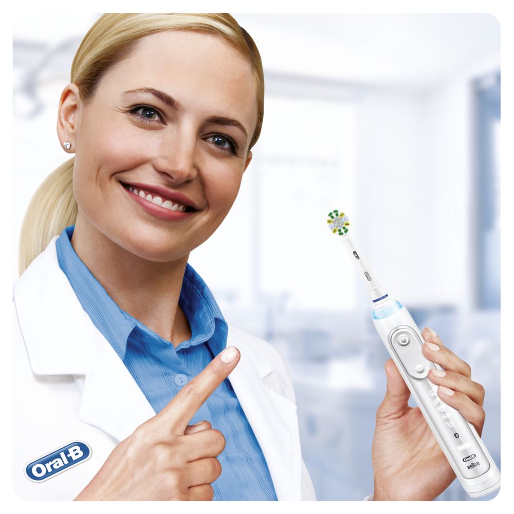 Eine Frau in einem weißen Kittel hält eine elektrische Zahnbürste. Auf der Zahnbürste steht Oral-B.
