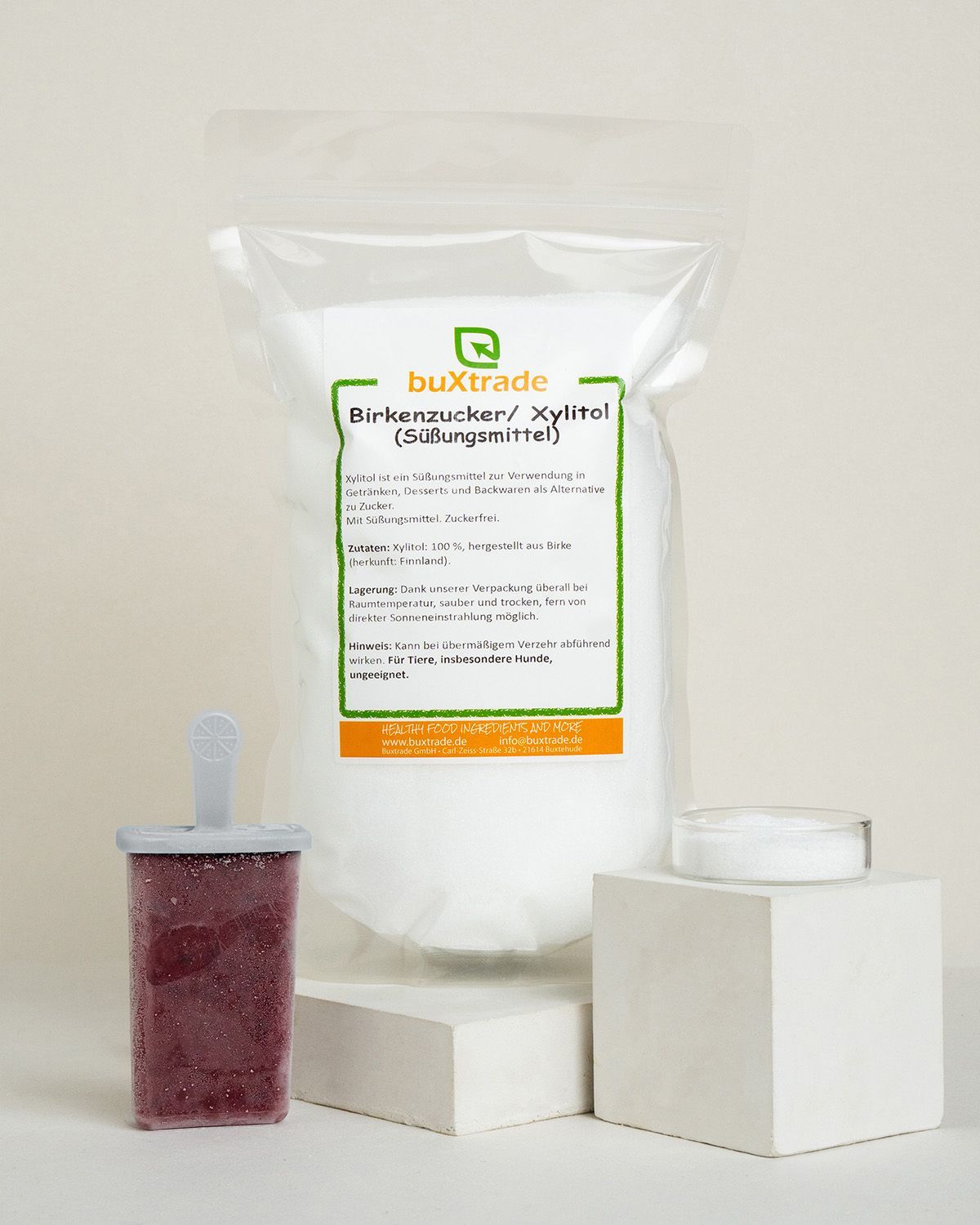 Verpackung mit Xylit, ein Fruchteis und ein kleiner Behälter mit Xylit auf Podesten.