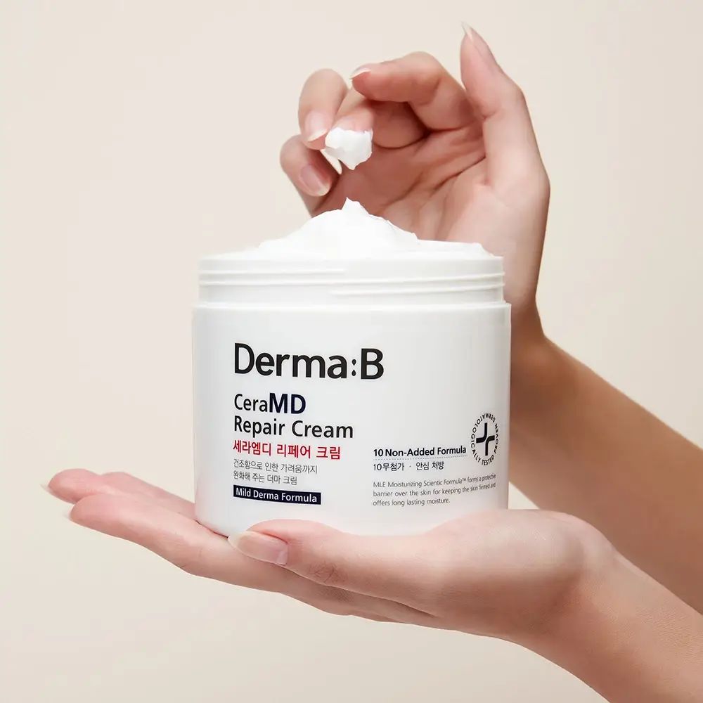 Hände halten offenen Tiegel mit weißer Creme. Aufschrift: Derma:B CeraMD Repair Cream.