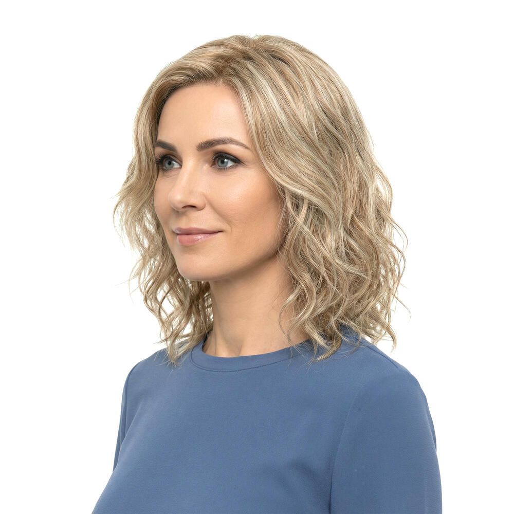 Frau mit blond gewellter Perücke. Seitenansicht. Die Perücke hat blonde und hellbraune Strähnen.