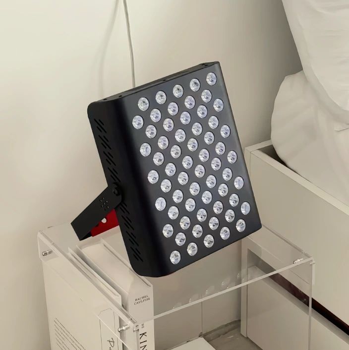 Schwarzes Gerät mit weißen Lichtern, Ständer. Rechteckige Form, viele runde Öffnungen. Auf Tisch.