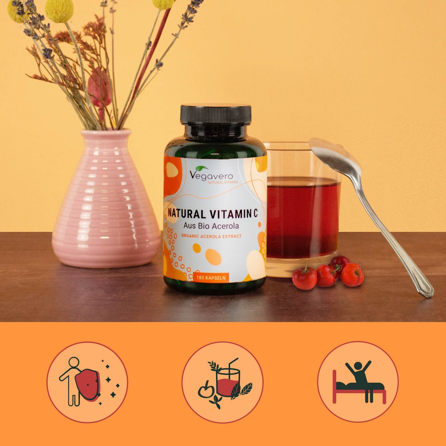 Grüne Flasche mit schwarzen Deckel. Aufschrift: Natural Vitamin C BIO. Zubehör: Vase, Glas, Löffel, Kirschen.