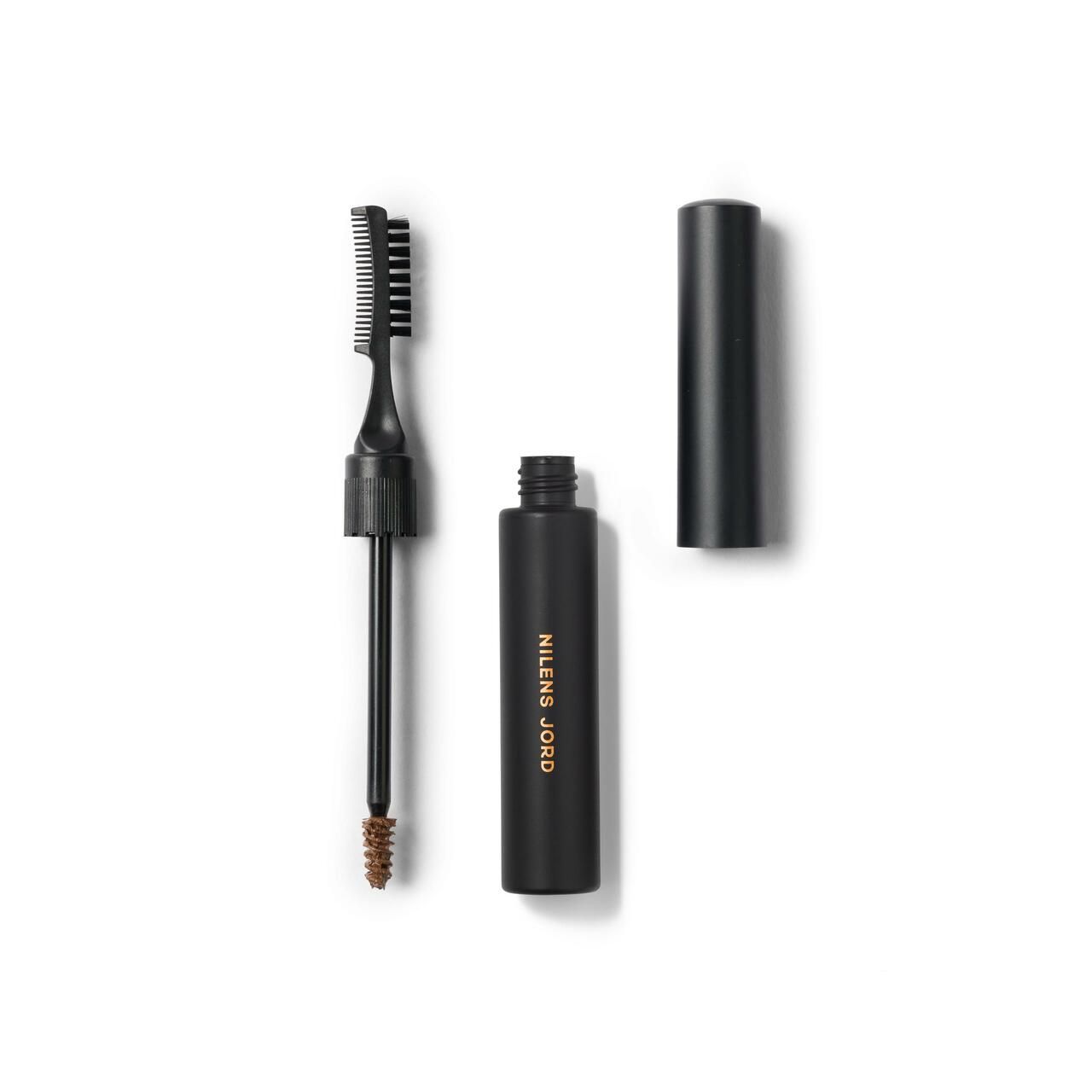 Schwarze Kosmetikflasche mit Bürste und Kamm. Aufschrift: Nilens Jord. Deckel daneben.