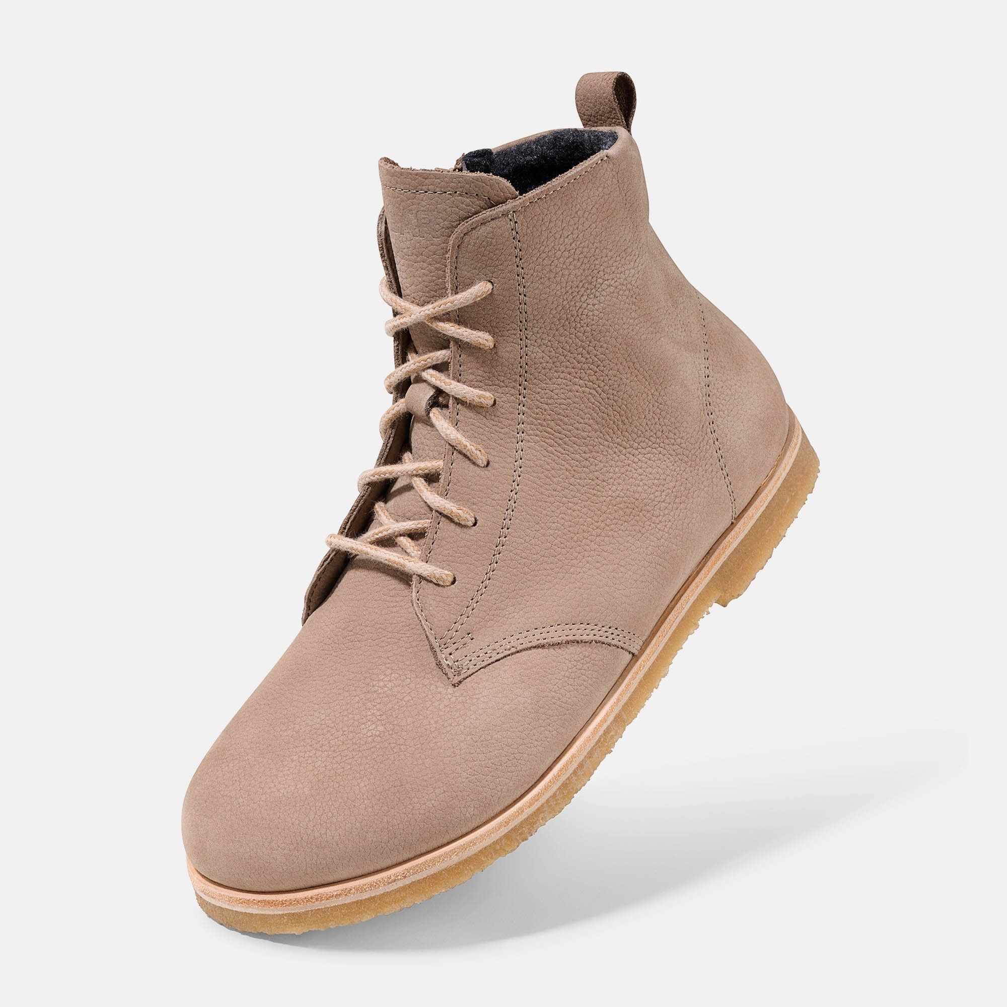 Beigefarbene Stiefelette mit Schnürung. Hellbraune Sohle, helles Leder. Flache Form, breite Passform. Perspektive.