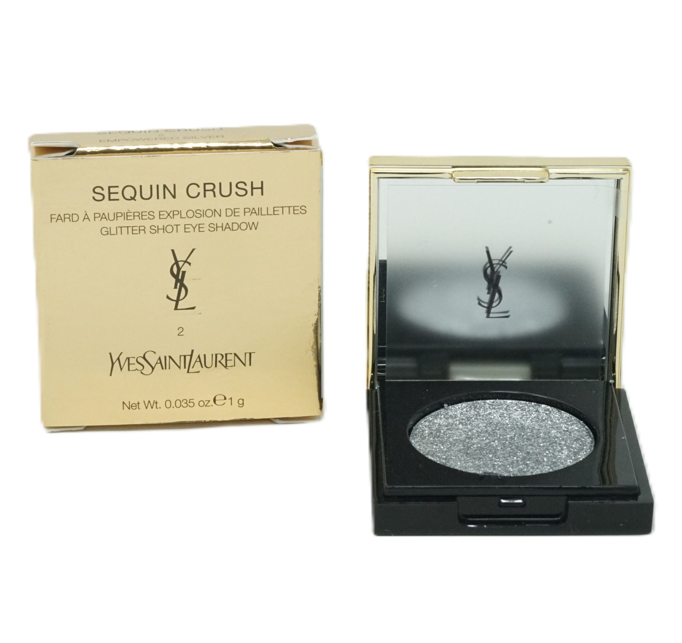 Lidschatten-Palette mit silbernem Glitzer. Schwarzer Behälter mit Spiegel und goldfarbener Umrandung. Goldfarbene Verpackung mit Markenlogo und Produktbezeichnung.