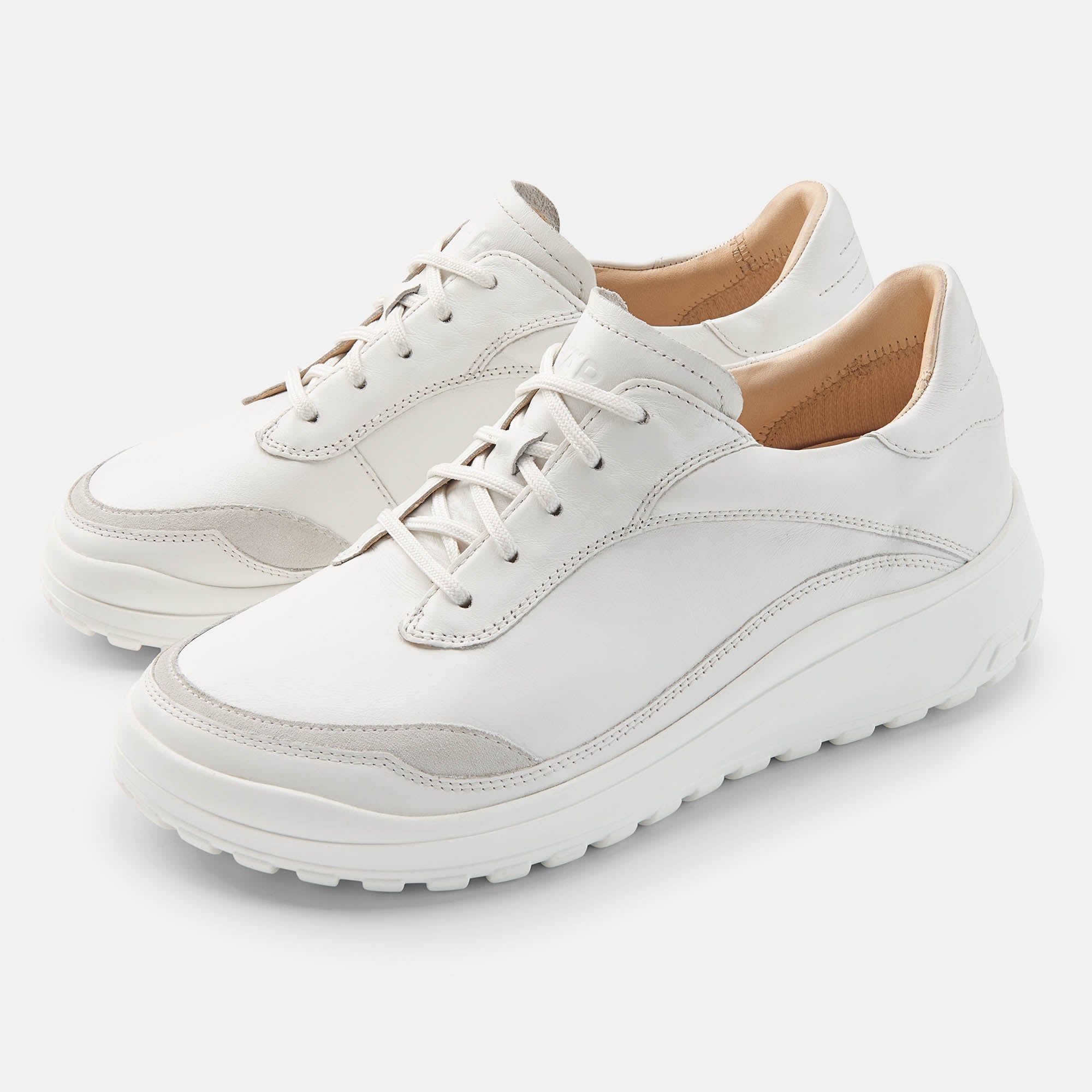 Zwei weiße Schnürschuhe. Runde Zehen, helle Sohle, Schnürsenkel. Hellgraue Akzente an der Zehenkappe. Innenfutter beige.