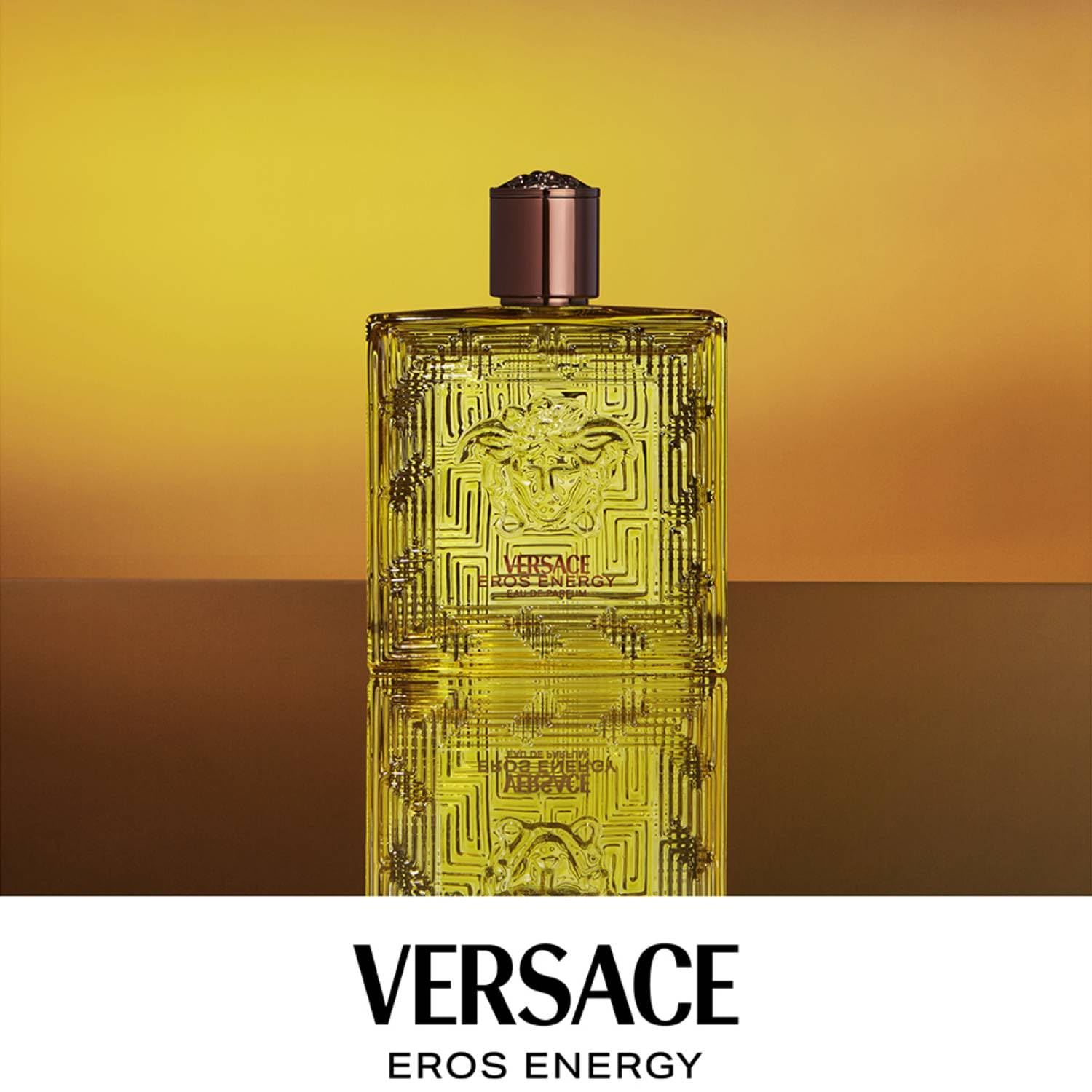 Gelber Flakon Versace Eros Energy. Brauner Verschluss. Quadratische Form mit Reliefmuster. Versace-Logo sichtbar.