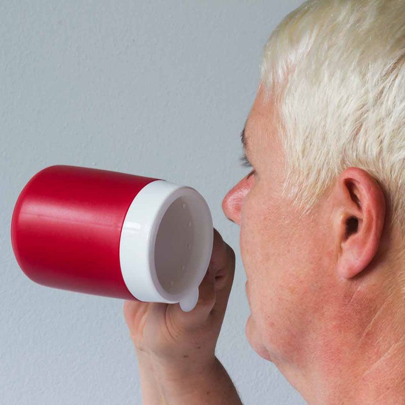 Person trinkt aus einem roten Becher mit weißem Trinkaufsatz. Der Becher wird gehalten.