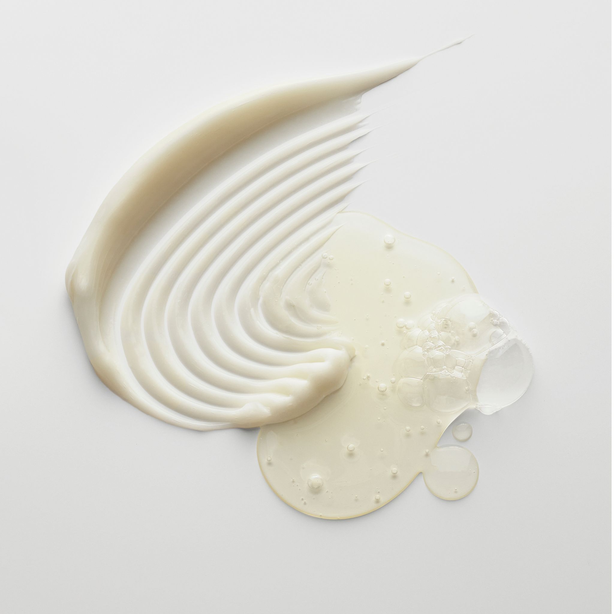 Texturproben von Conditioner und Serum auf weißem Hintergrund.