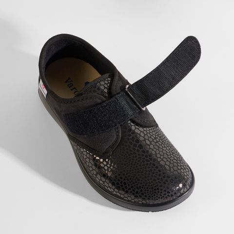 Schwarze Damenschuhe mit Klettverschluss, gemustertem Obermaterial und sichtbarer Sohle.