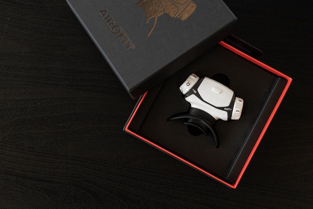 Atemtrainer in schwarzer Box. Weißes Gerät mit schwarzem Mundstück. Box mit Airofit-Logo.