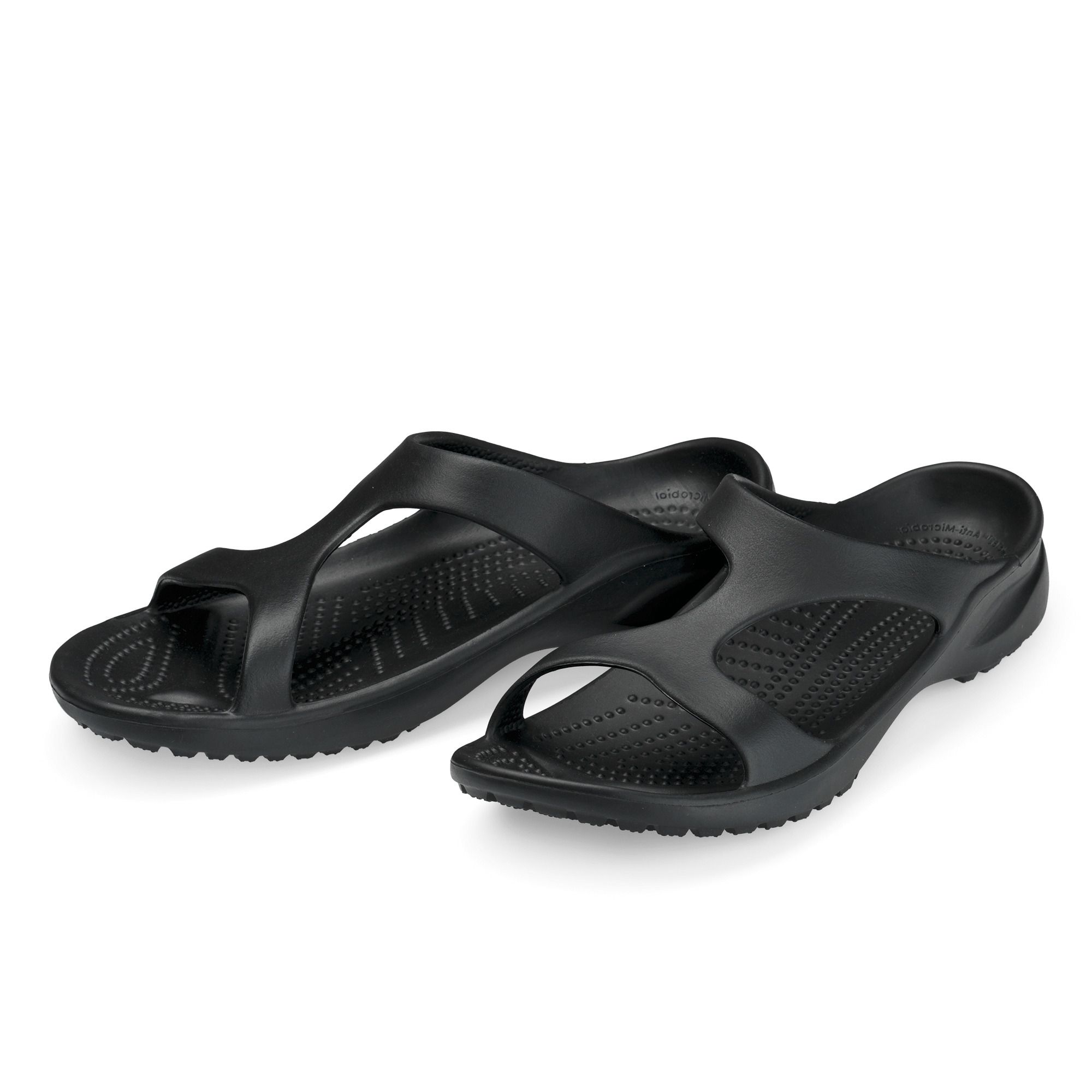 Schwarze Pantoletten. Breite Passform. Offene Zehen. Geformte Sohle. Zwei Schuhe nebeneinander.