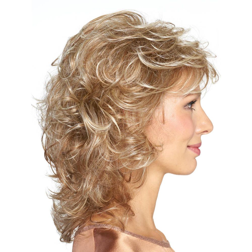 Profil einer Frau mit blond gelockter Perücke. Die Perücke hat einen Pony und ist leicht gestuft. Sie trägt ein helles Oberteil.