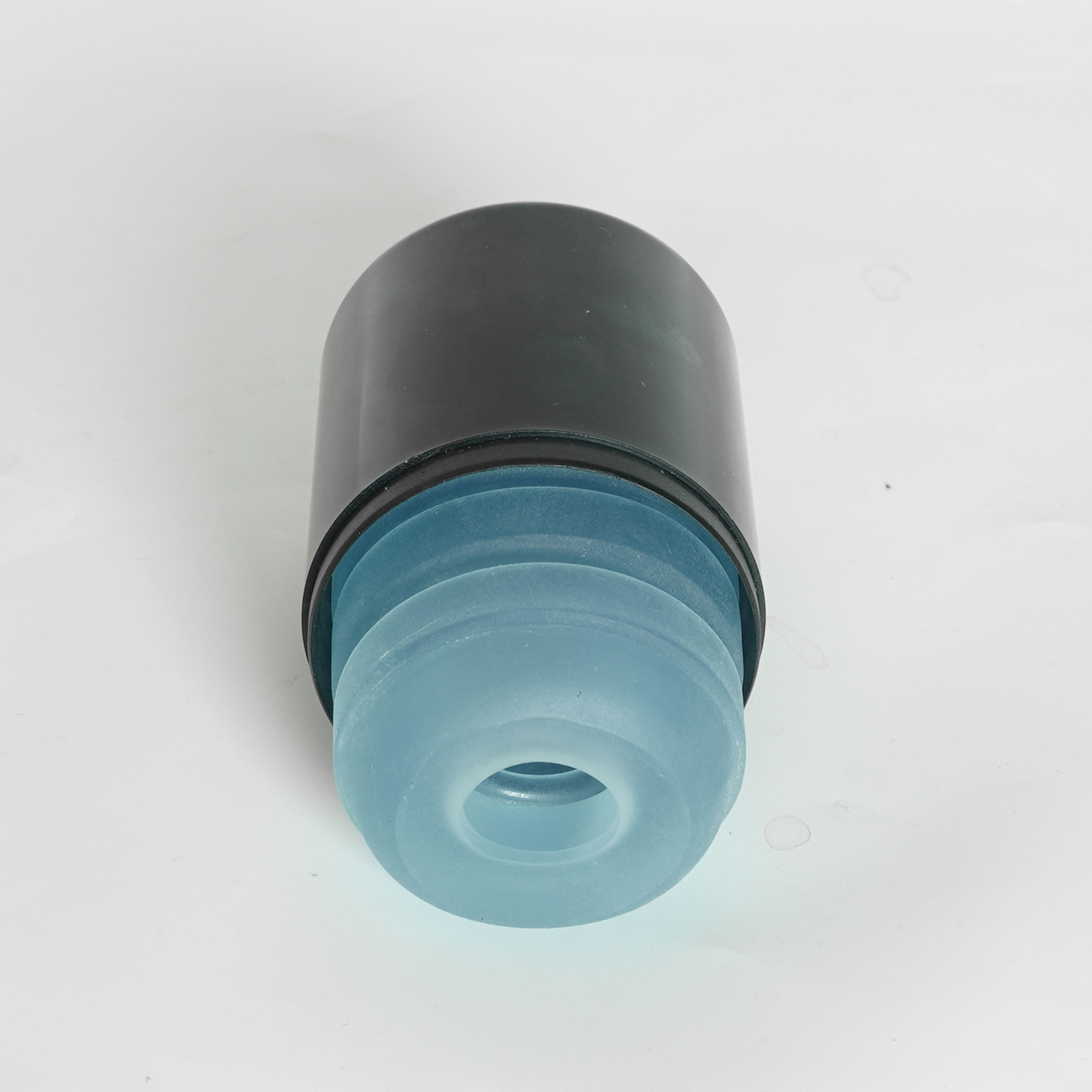 Blaues Silikonprodukt in schwarzem Behälter. Mehrere Ringe sichtbar. Auf weißem Hintergrund.